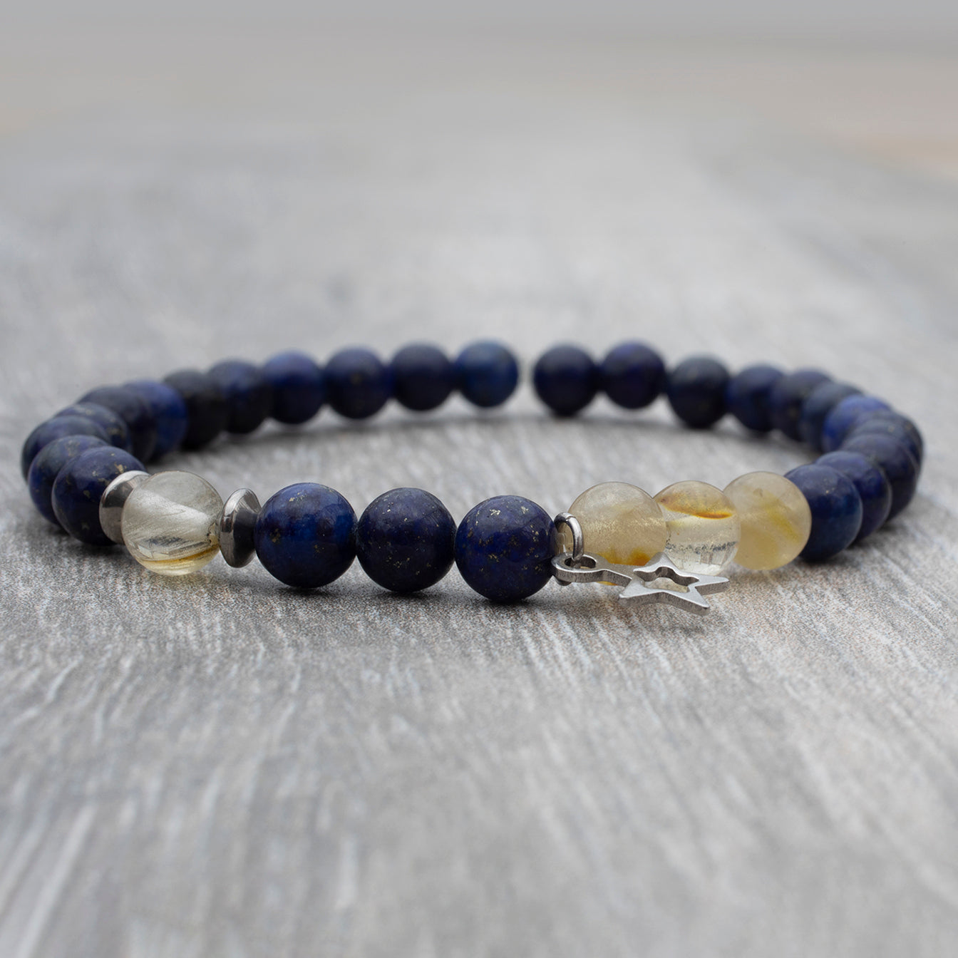 Bracelet de couleur noir avec des pierres de lapis lazuli  et de fines quartz beige. Breloque en étoile.