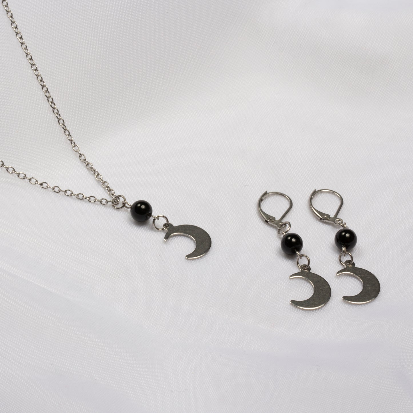 Duo colliers et boucles d'oreille à base d'améthyste avec de l'acier inoxidable pour former la lune qui sert de pendant sur fond blanc