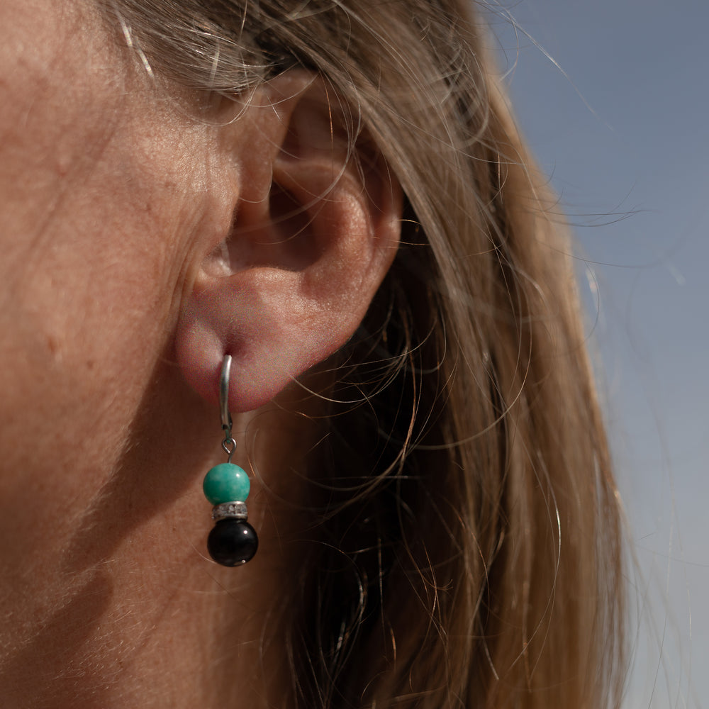 
                  
                    Femme arborant une paire de boucles d'oreilles en jade et pierres fines noires
                  
                