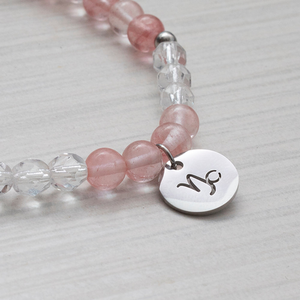 Breloques signes astrologiques sur un bracelet de pierres transparentes et roses