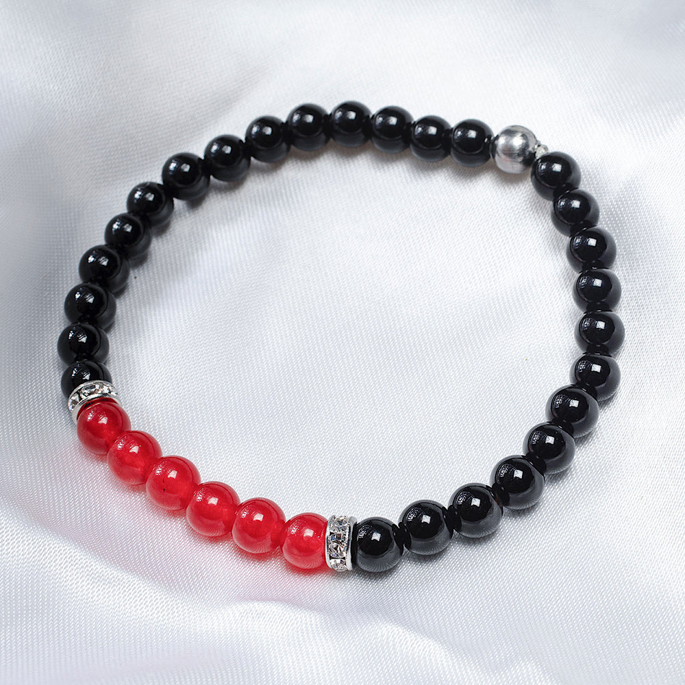 
                  
                    Bracelet composé d’onyx noir et de jade rouge déposé sur un fond blanc.
                  
                