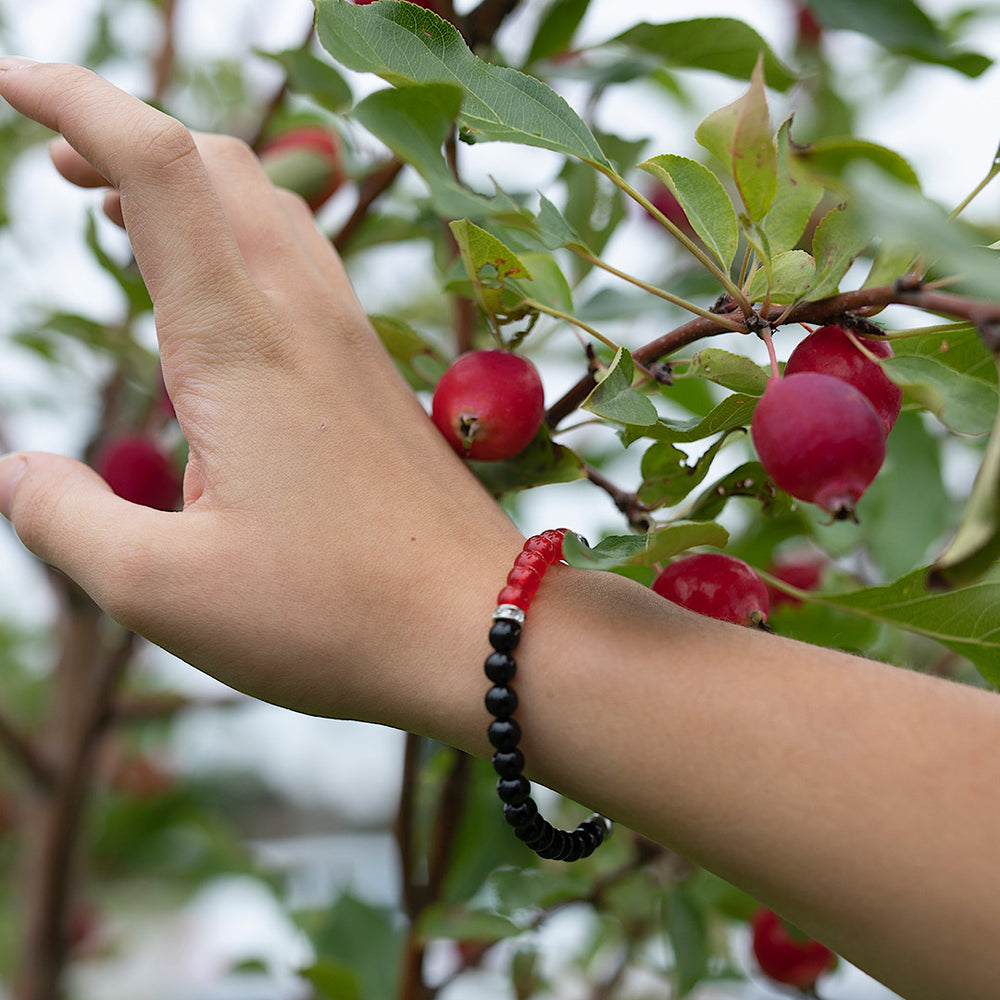
                  
                    Poignet de femme prêt d'un arbre fruitier avec un bracelet rouge et noir d'Ovie Bijoux
                  
                