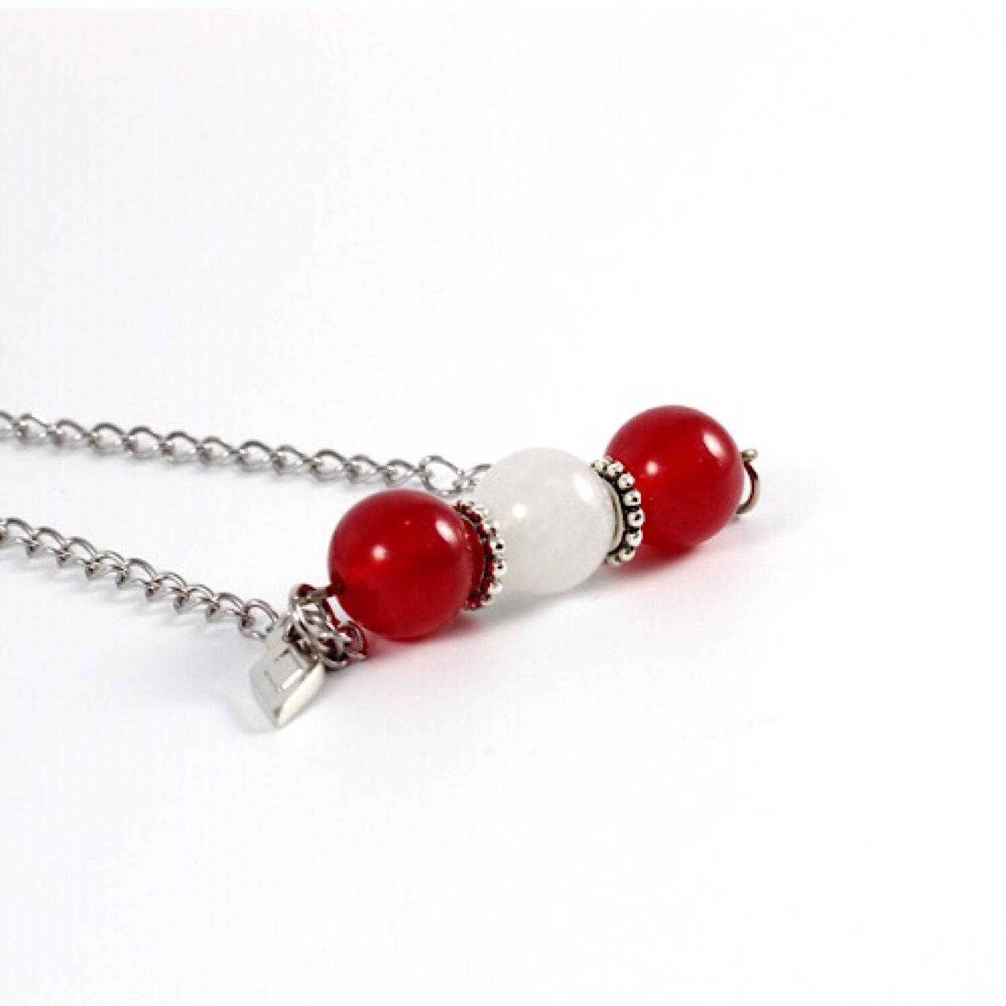 
                  
                    Joli collier composé de pierres fines jade rouge et jadeDétail du collier Mia avec des pierres de jade blanc et rouge, sur une chaîne en acier inoxydable.
                  
                