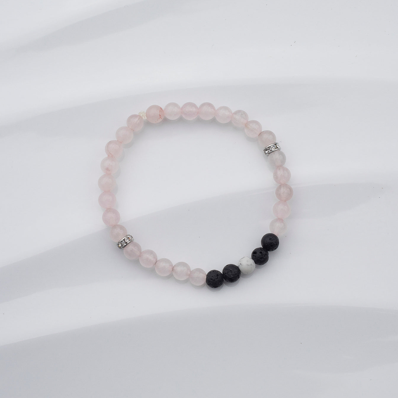 Bracelet de quartz rose, howlite et pierres volcaniques noires sur fond blanc
